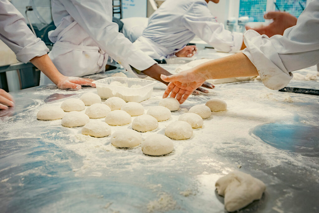équipe de pâtissiers façonnant des pâtons en laboratoire illustrant la production en coffee shop et la reformulation de recettes